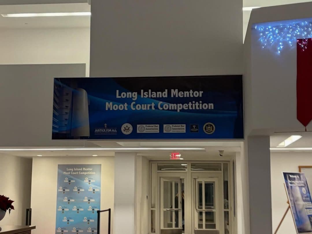 A long illuminated banner mounted above a doorway in a lobby, reading Long Island Mentor Moot Court Competition above a row of bar association seals.